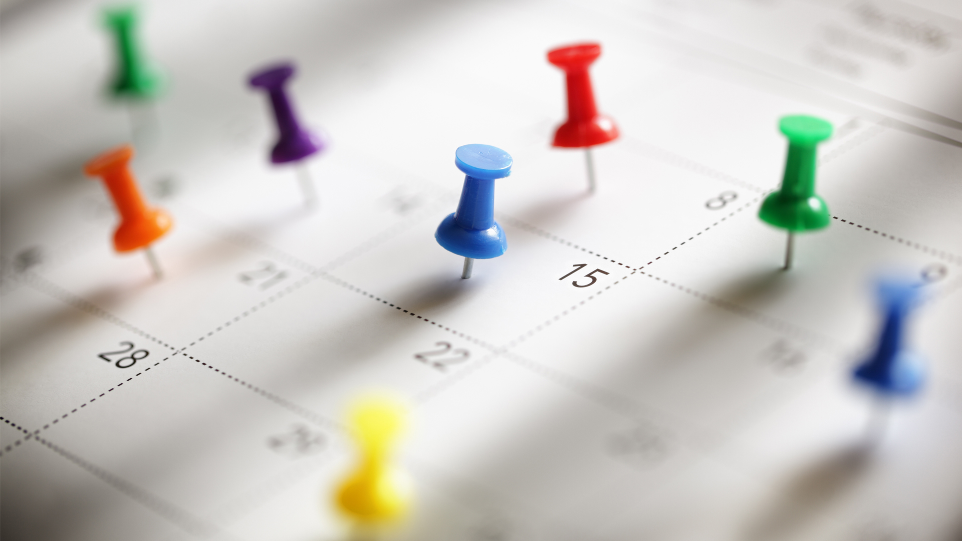 Calendar of events. Colorful pushpins on a white calendar.