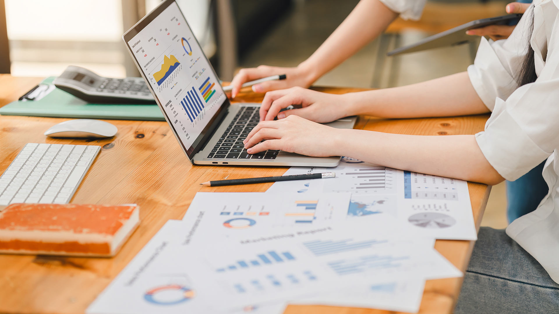 Professional working on colorful charts and data spreadsheets displayed on a laptop.