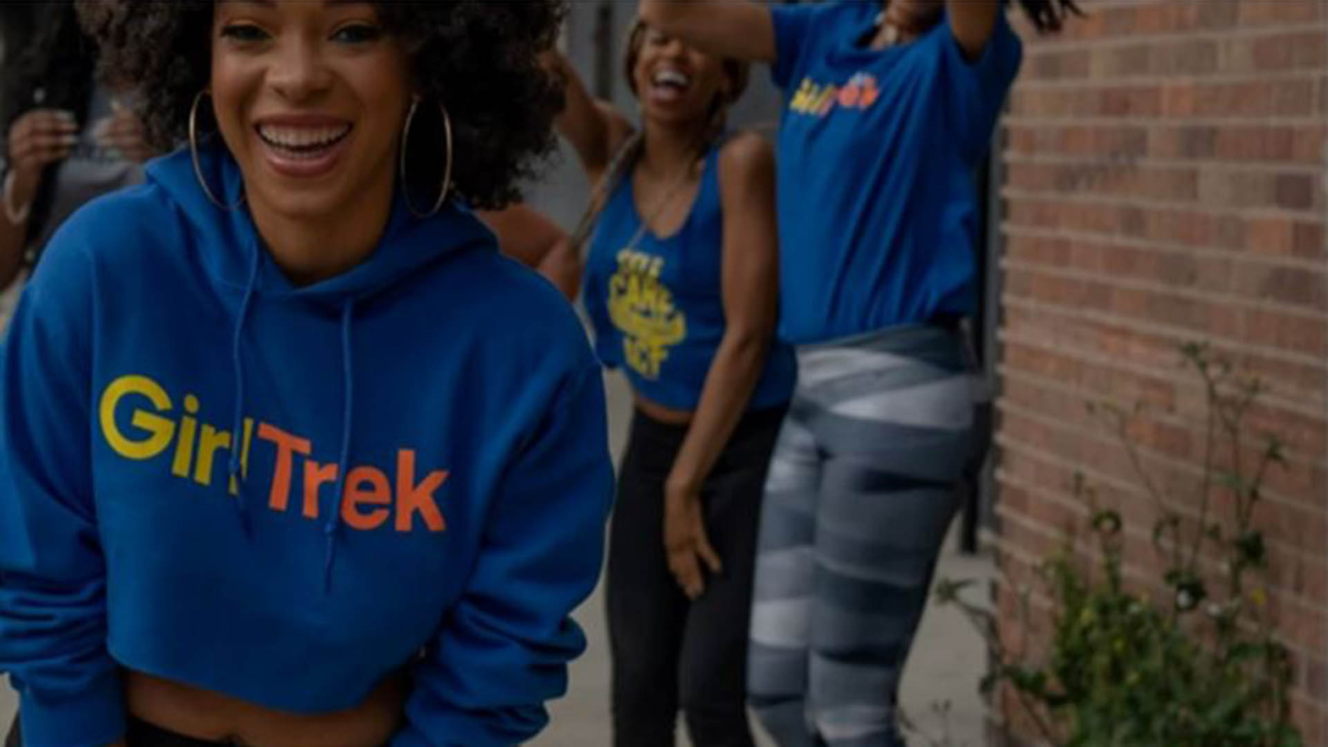 GirlTrek, image of women of color in blue sweatshirts outdoors smiling and celebrating