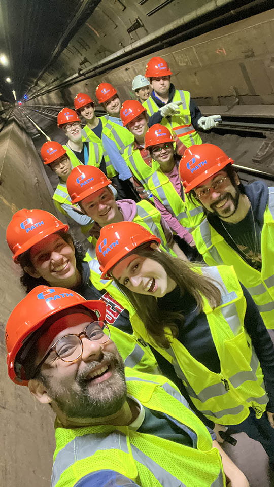 Students wearing yellow reflective vests and orange hardhats participating with Bloustein Enthusiasts and Advocates for Transportation (BEAT) took part in an exclusive after-hours PATH (Port Authority Trans-Hudson) tour.
