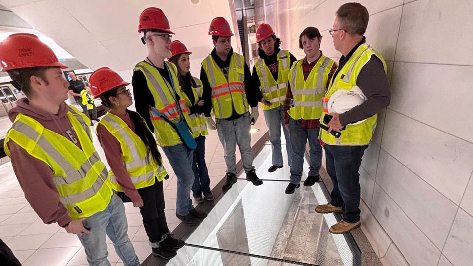 Students wearing yellow reflective vests and orange hardhats participating with Bloustein Enthusiasts and Advocates for Transportation (BEAT) took part in an exclusive after-hours PATH (Port Authority Trans-Hudson) tour.