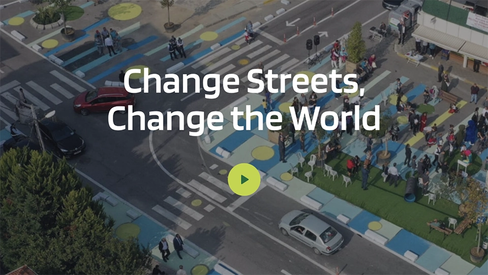 Designing Streets for People event. Text Change Streets, Change the World overlaid on a background of an illustrated city street with people and buildings